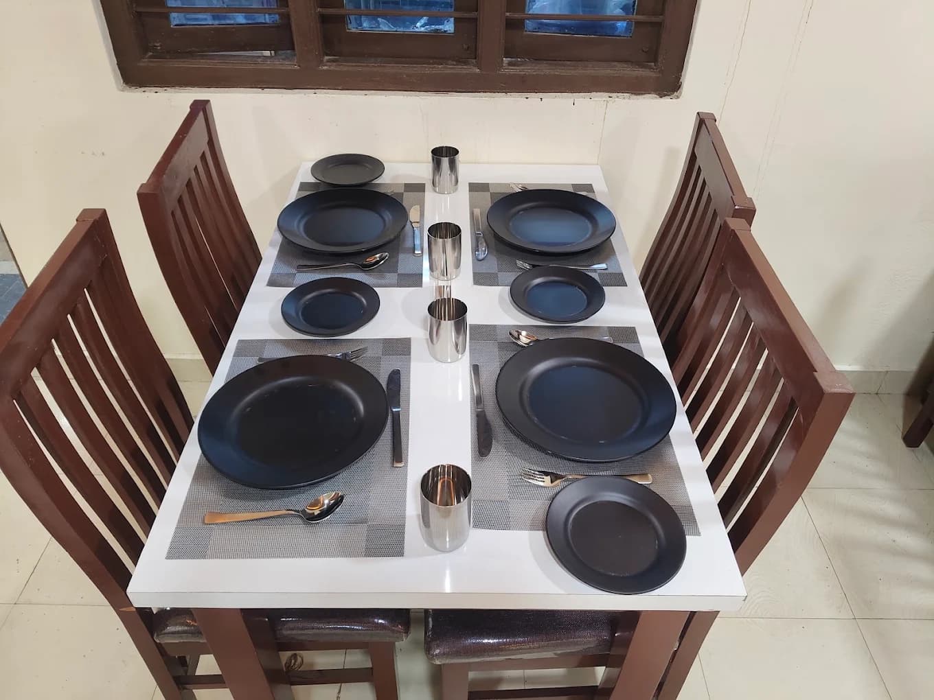 A table for four set with black plates and cutlery at Bharathi Kitchen
